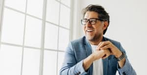 Smiling man in blue blazer near window.