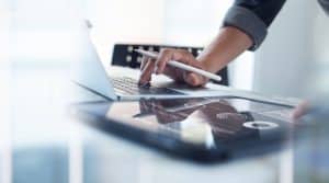 Person working on laptop with digital tablet