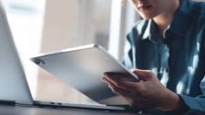 Person using tablet and laptop indoors.