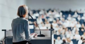 Speaker at podium addressing large audience