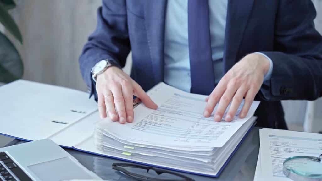 Professional reviewing documents on a glass desk.