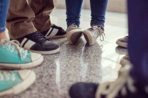 Group of feet in colorful sneakers on floor.