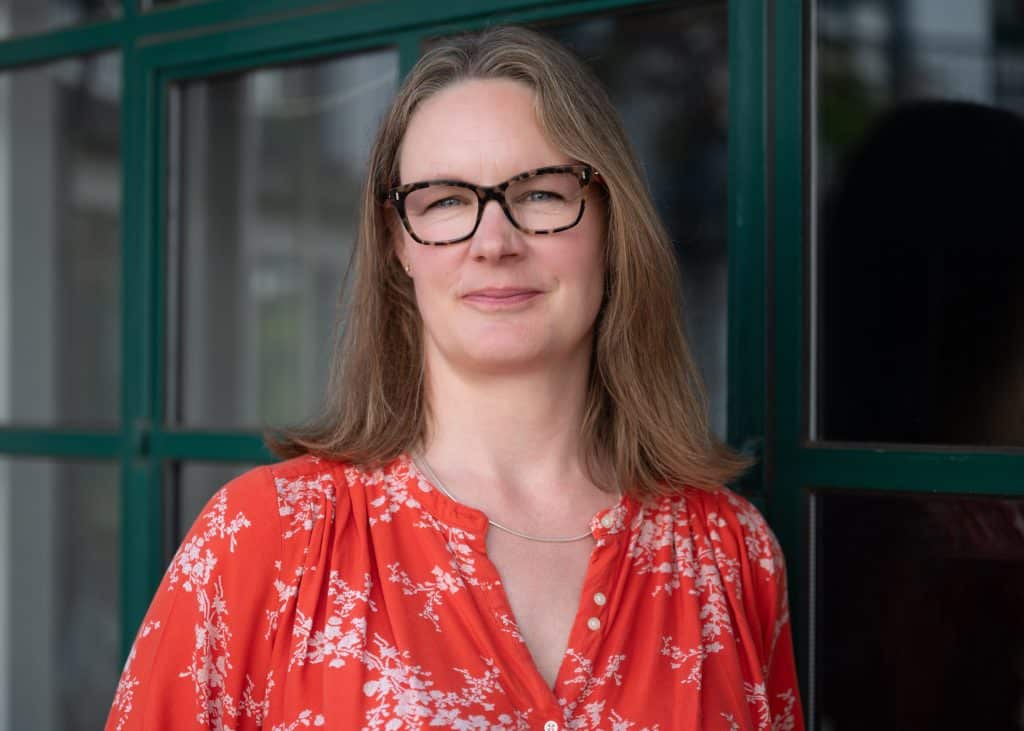 Person in glasses and floral red blouse smiling