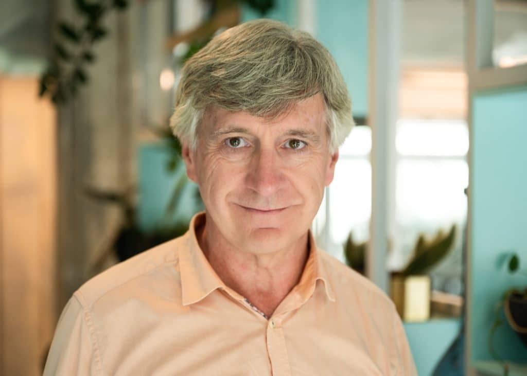 Elderly man smiling in an office environment.