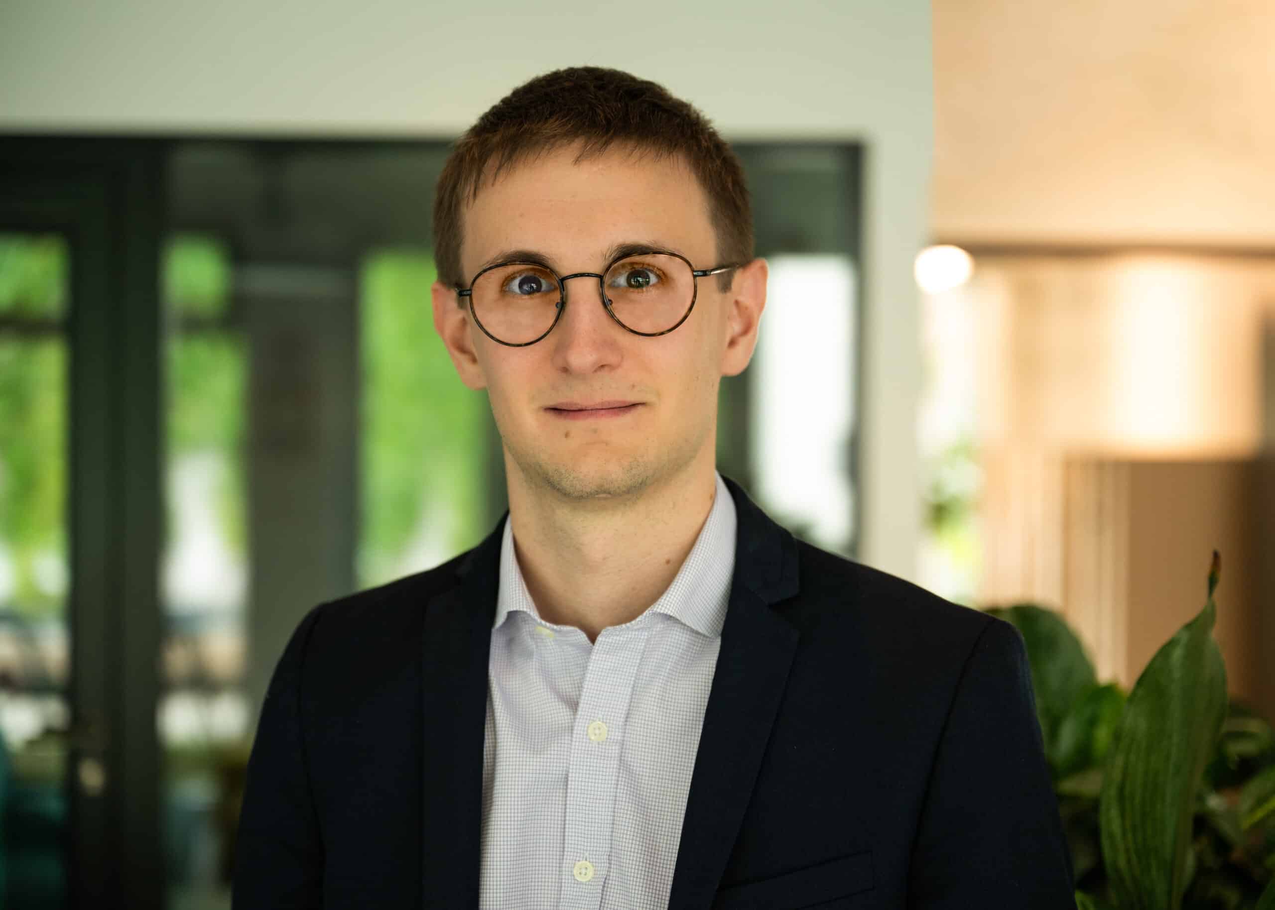 Man in a suit with glasses in an office.