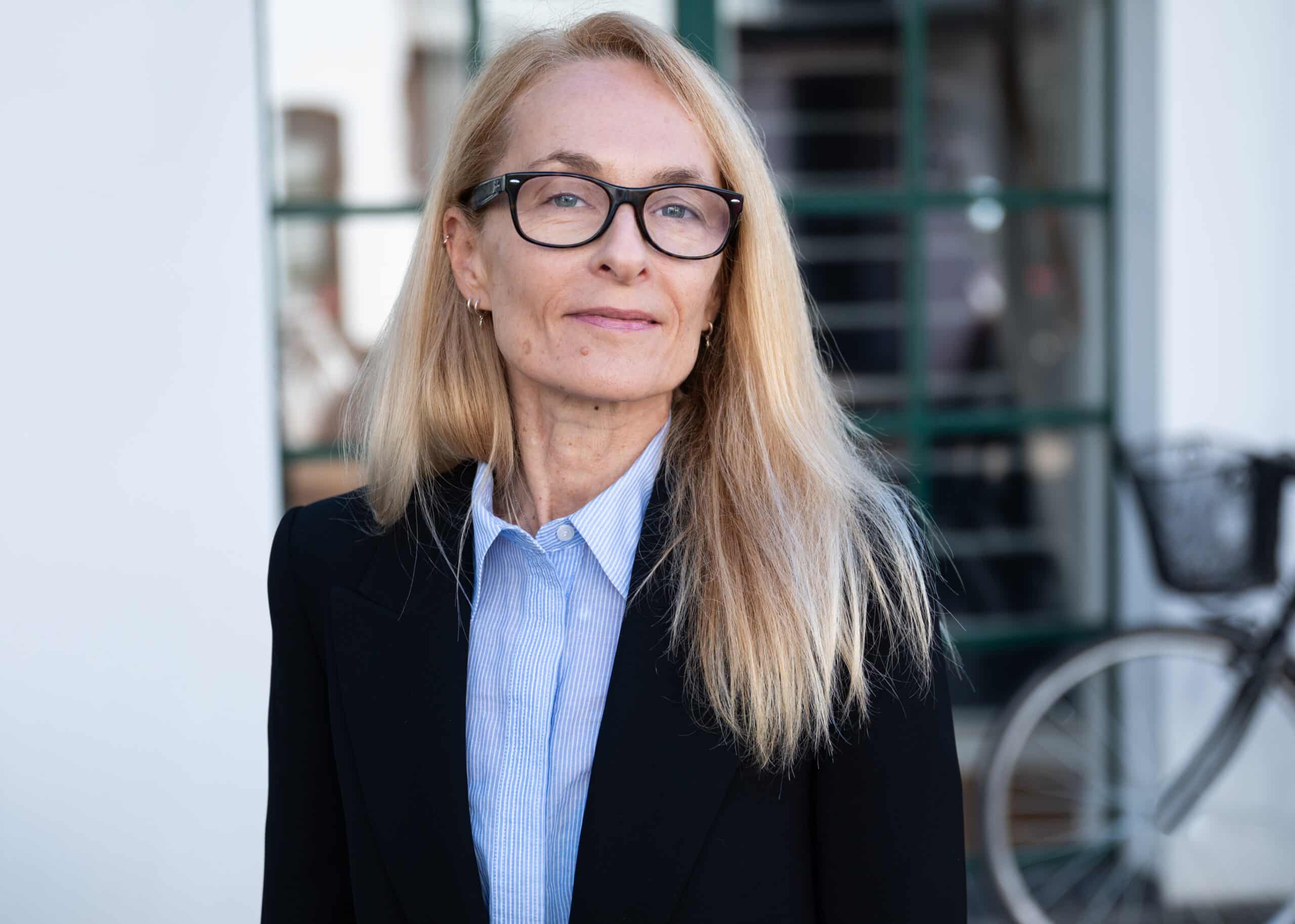 Woman with long blonde hair in professional attire.