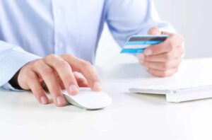 Person shopping online with credit card and mouse.
