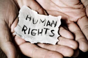 Hands holding torn paper with 'Human Rights' text.