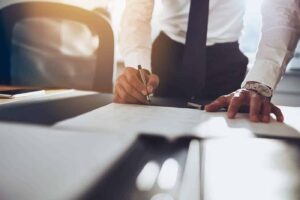 Person signing documents at a desk.