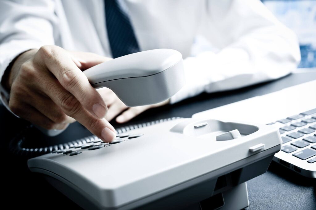 Person dialing a number on a telephone.