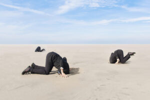 People in suits digging into sandy ground