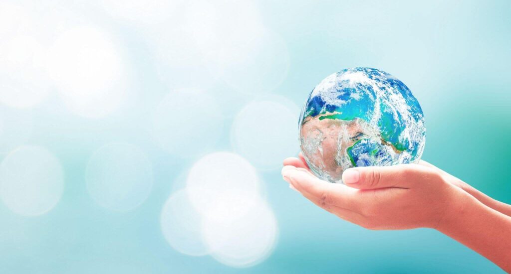 Hands cradling Earth against soft background