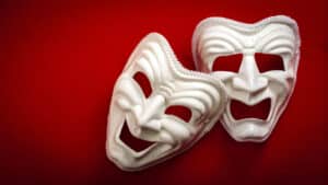 Two theatrical masks on a red background.