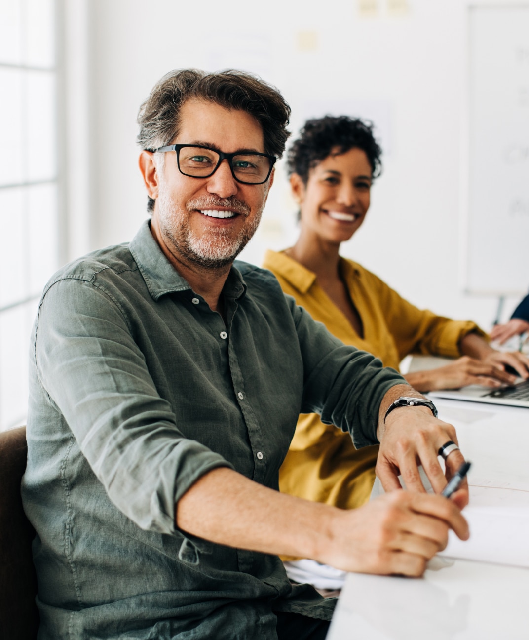 Man sat at a desk smiling at the camera
