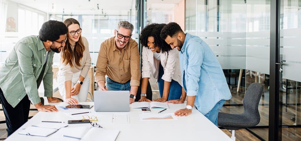 Team collaborating around a laptop in office