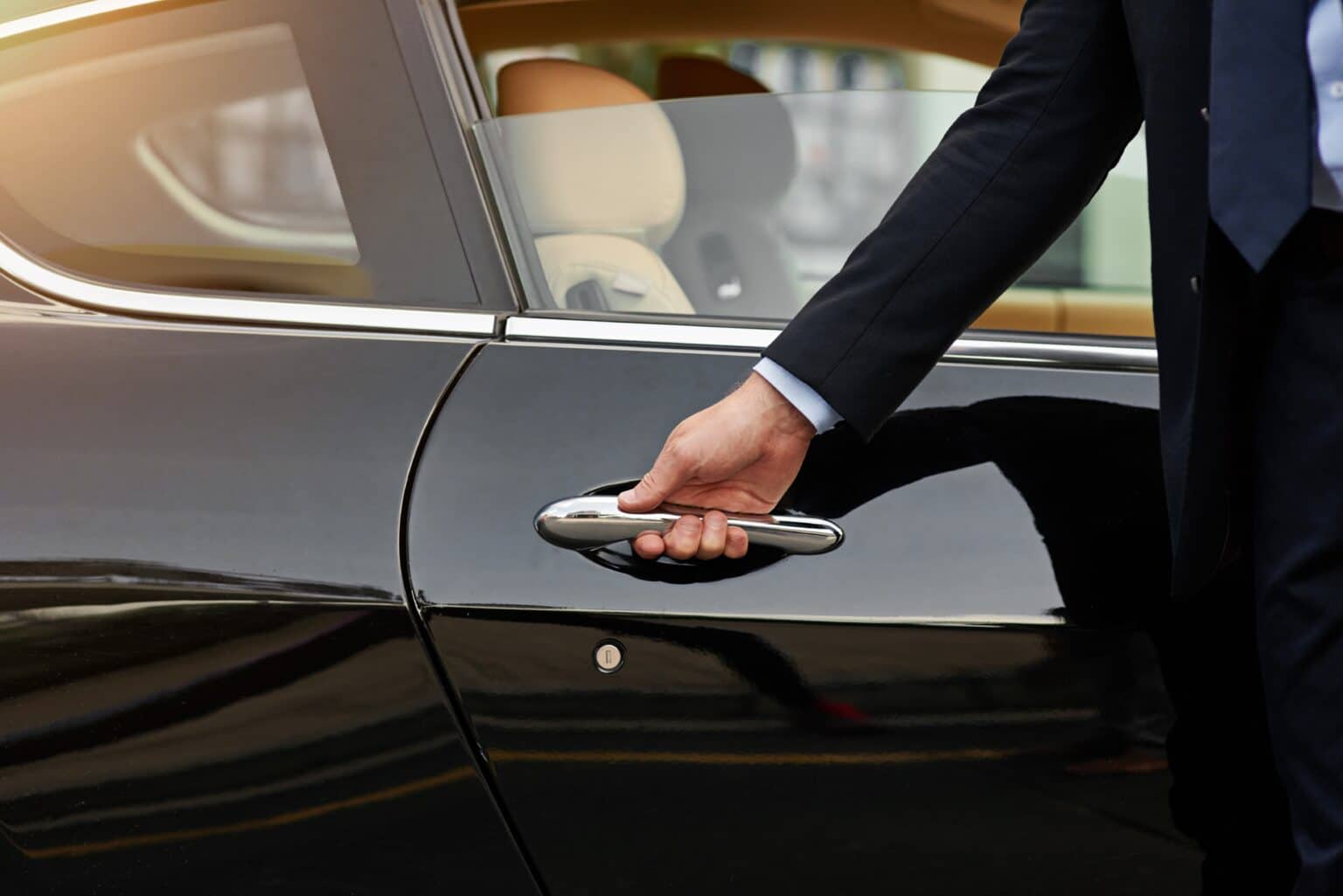 Person reaching for a car door handle.