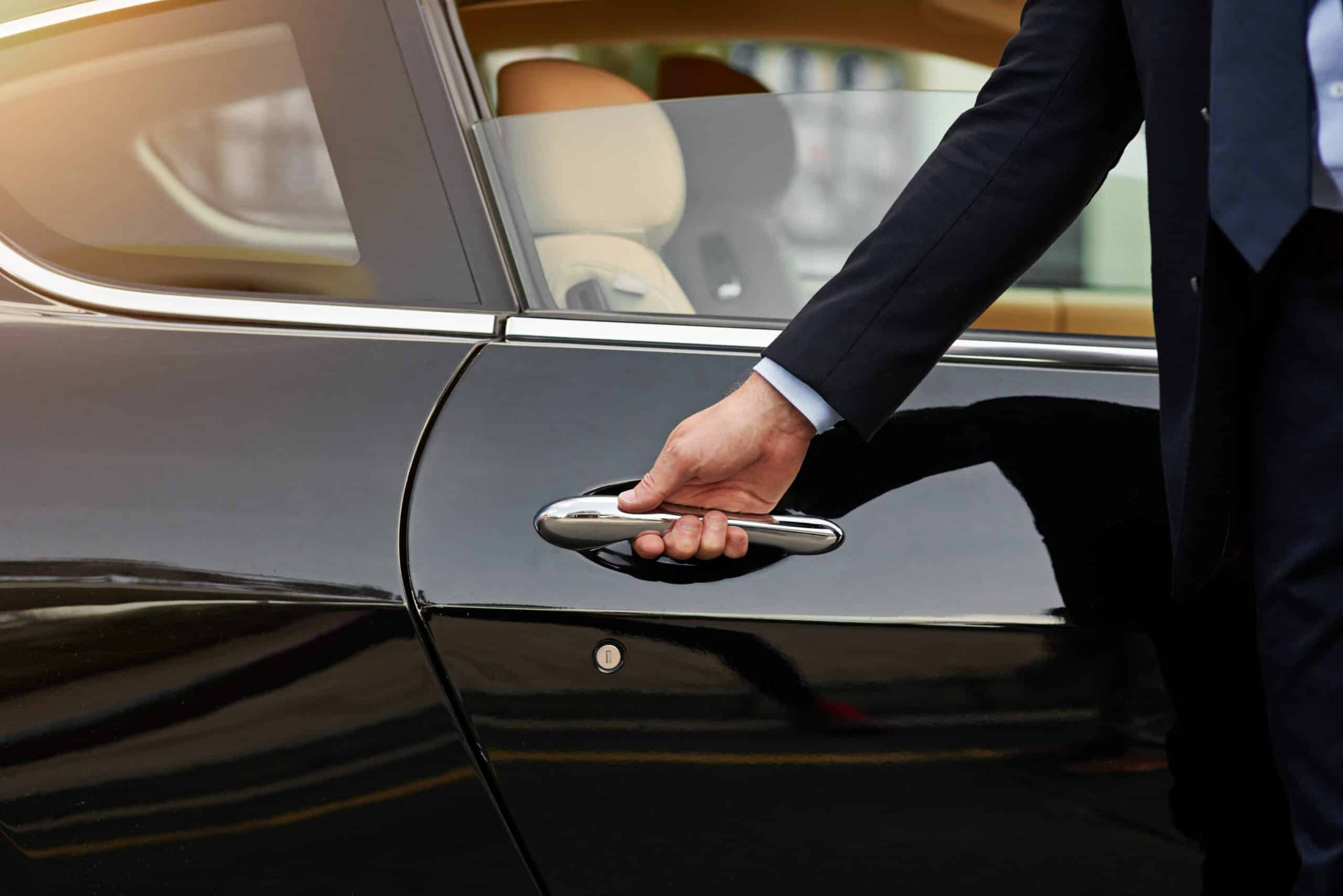 Person reaching for a car door handle.