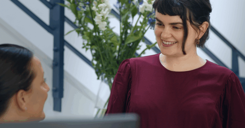 Two women smiling and chatting indoors.