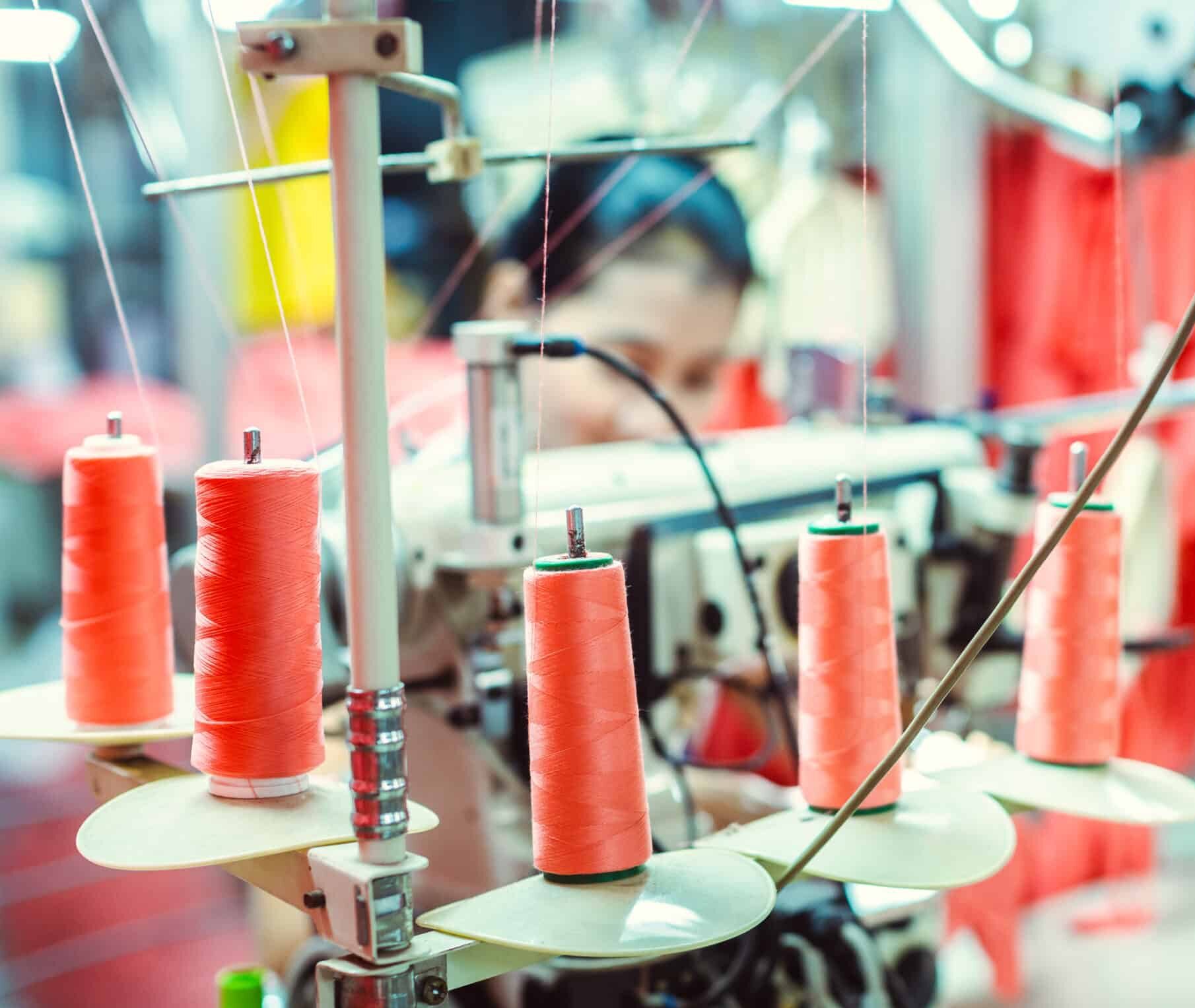 Spools of orange thread on a sewing machine.