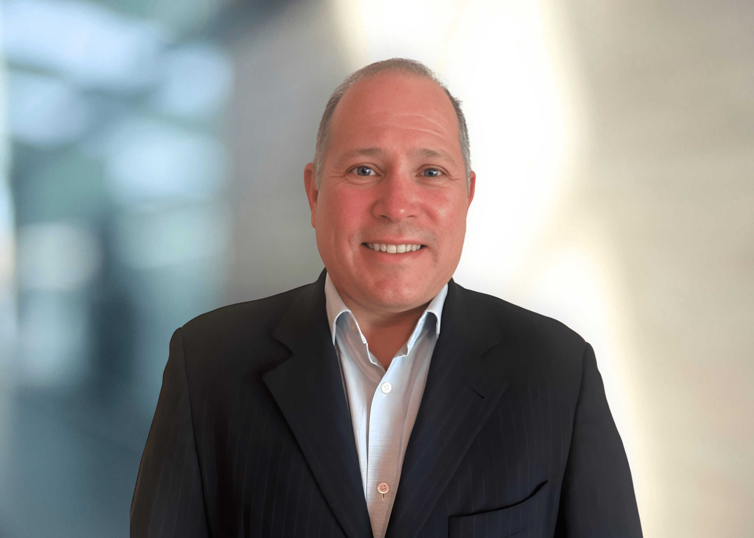 Smiling man wearing a suit against a blurred background.