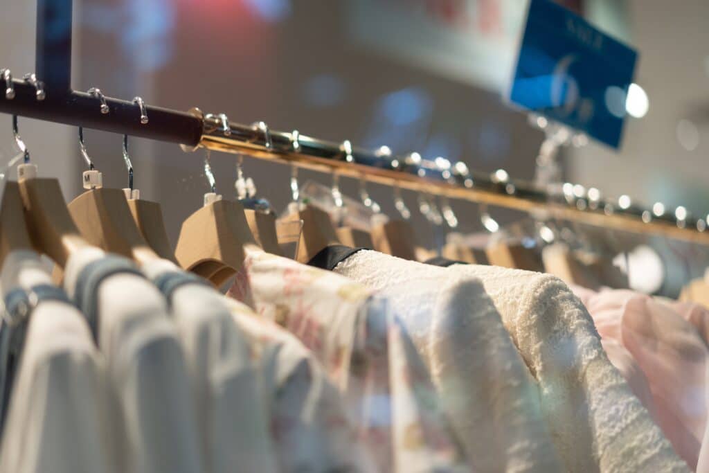 Clothes hanging on wooden hangers in a store.