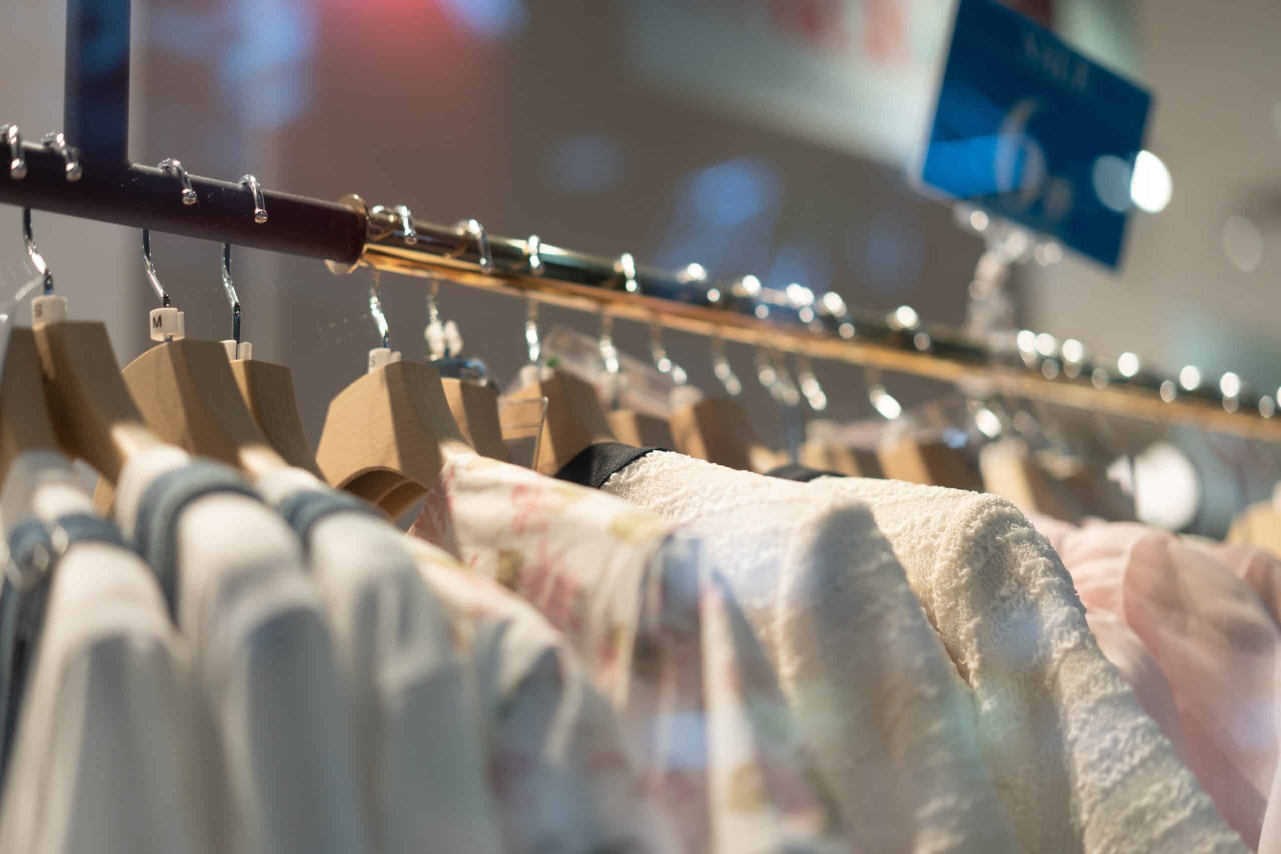 Clothes hanging on wooden hangers in a store.