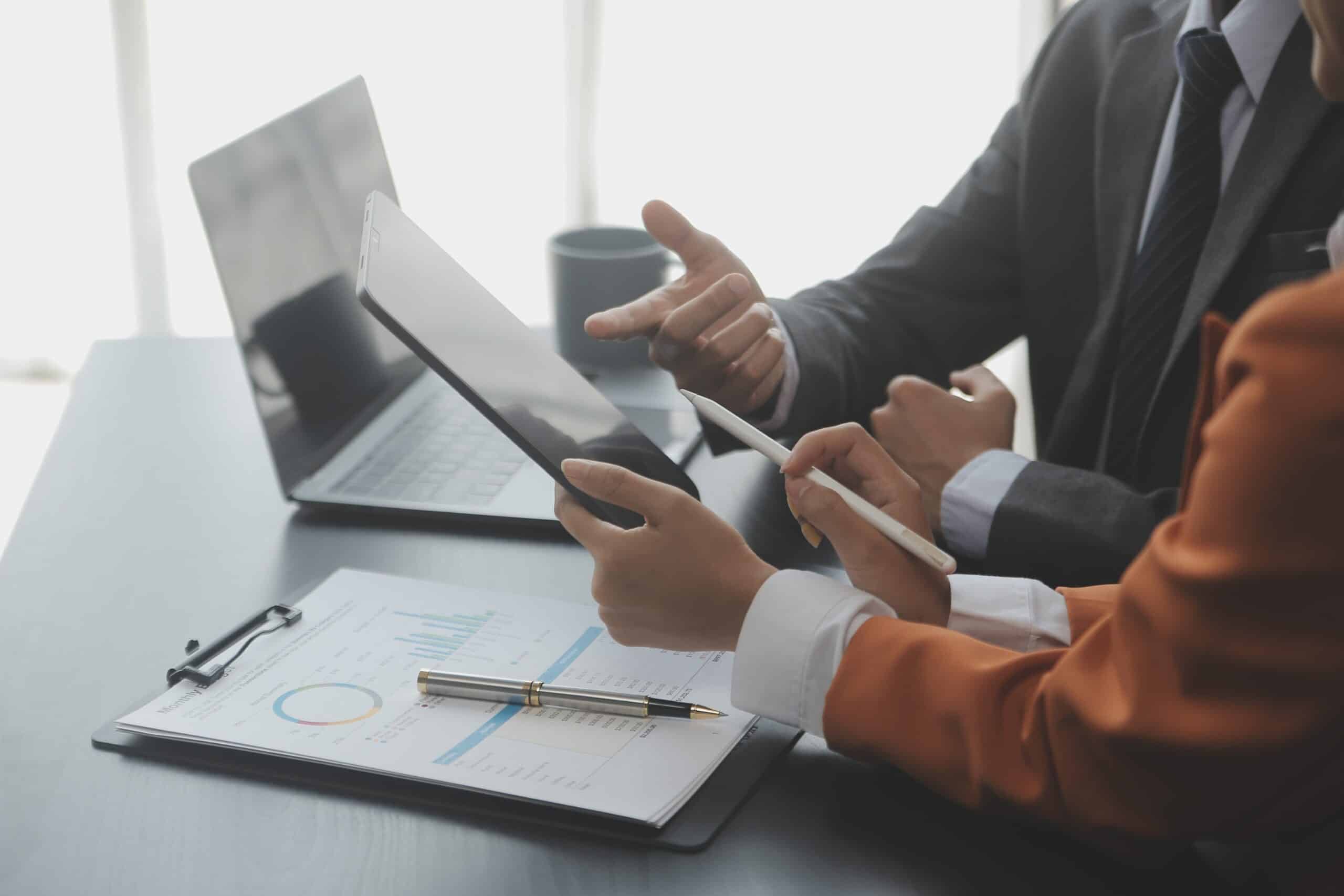 Professionals reviewing financial data on tablet in office