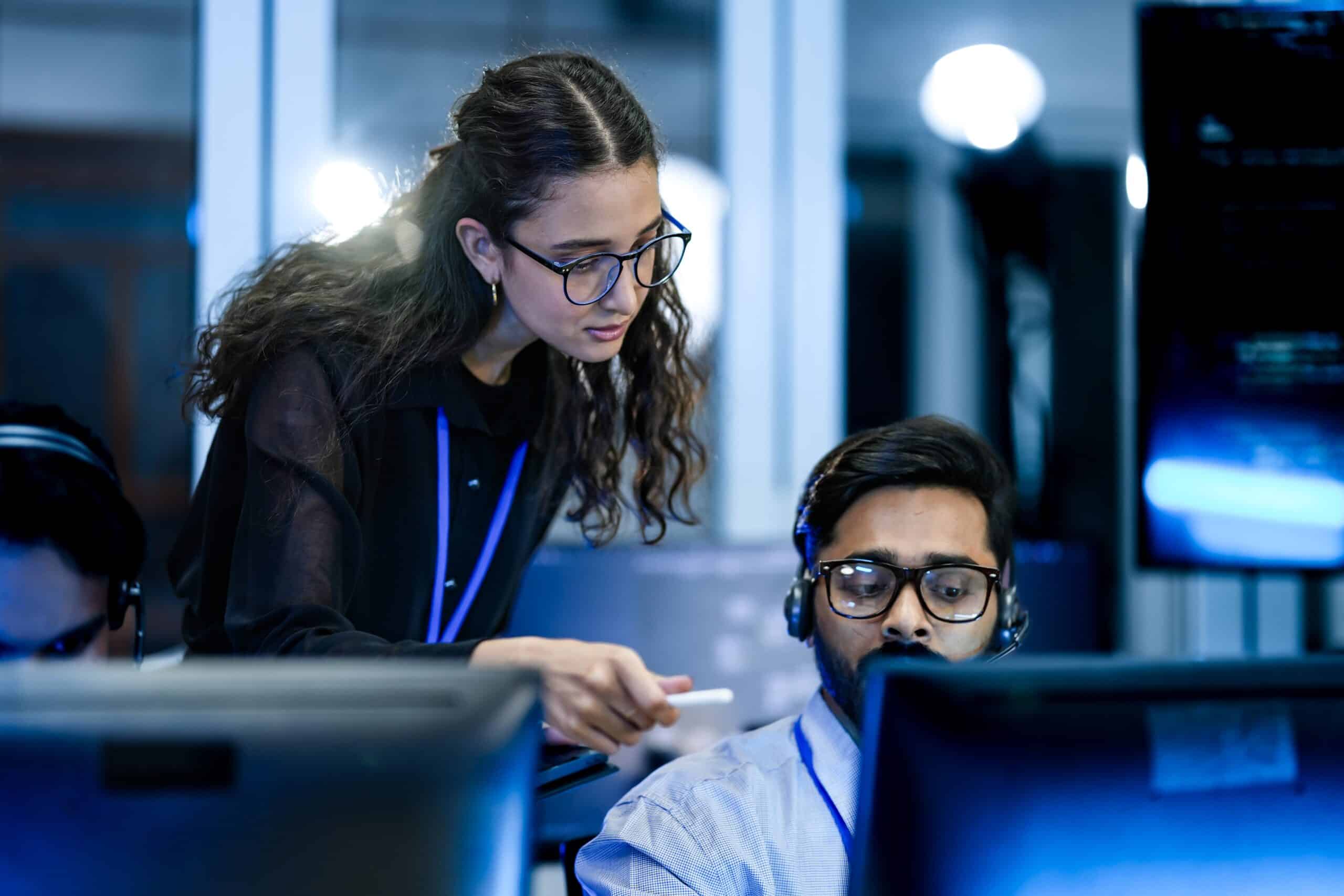 Woman assisting a man at computer workstation