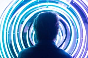 Person silhouetted against glowing neon light rings