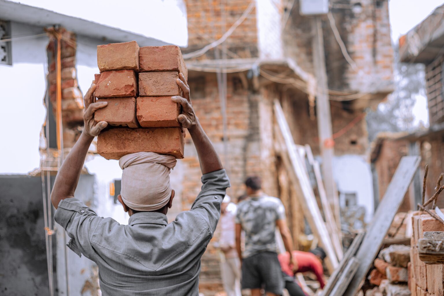 Construction worker carrying bricks on head at site