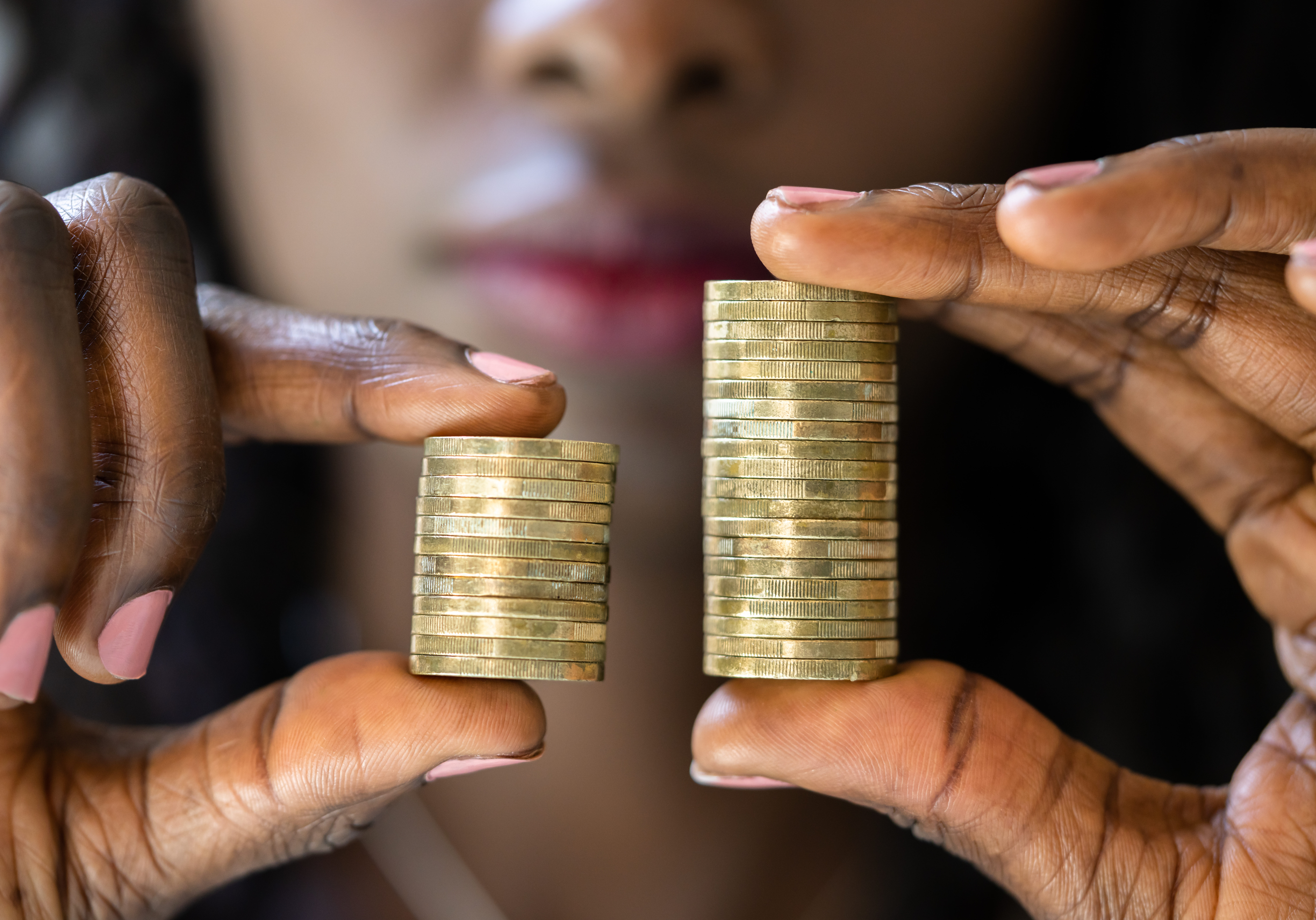 Woman holding up two stacks of coins to represent pay gaps
