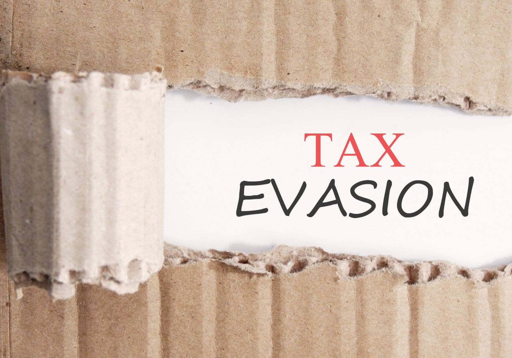 cardboard being ripped to show the words 'tax evasion'